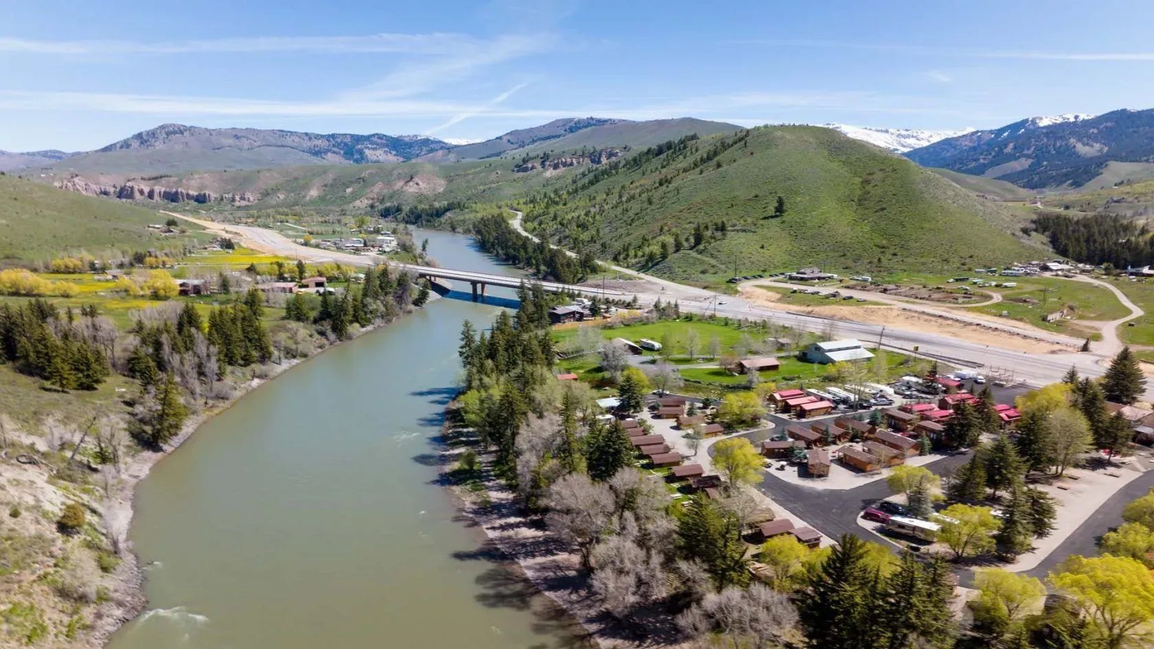 Aerial view of Snake River Cabins & RV Village alongside a river and bridge.