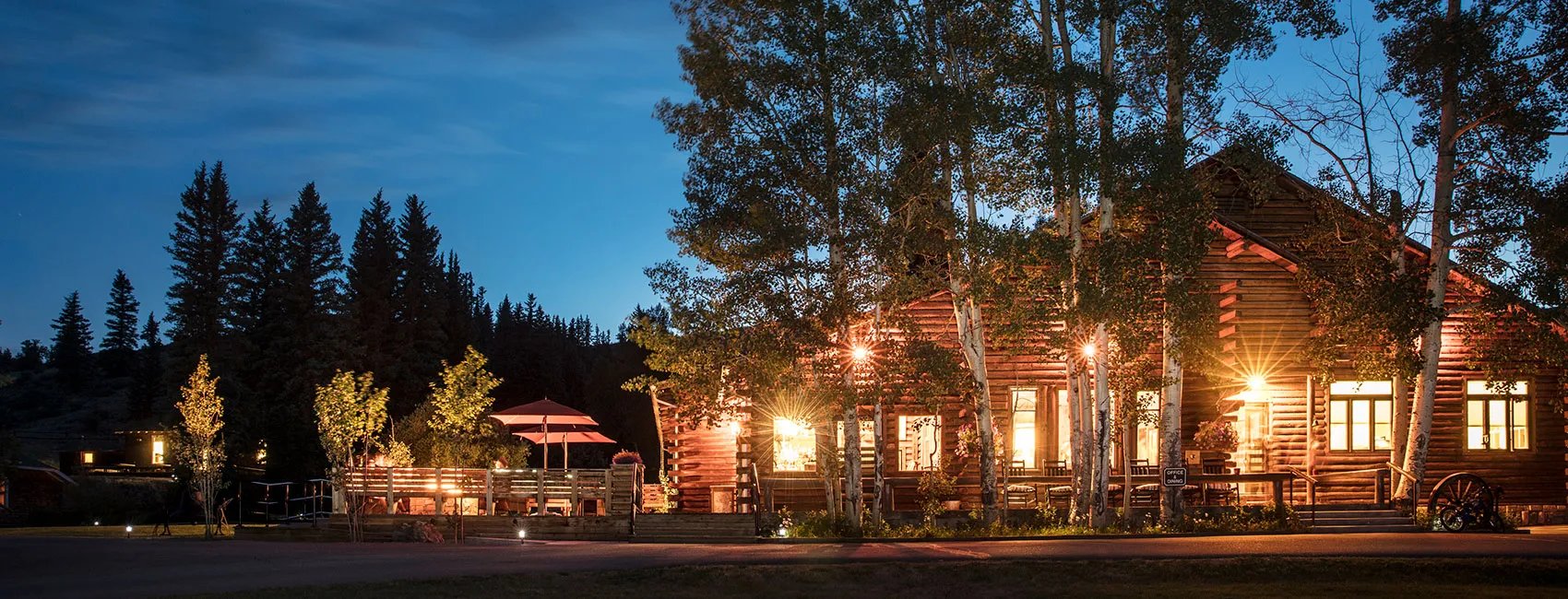 Main lodge building illuminated at dusk with warm lights glowing from windows.