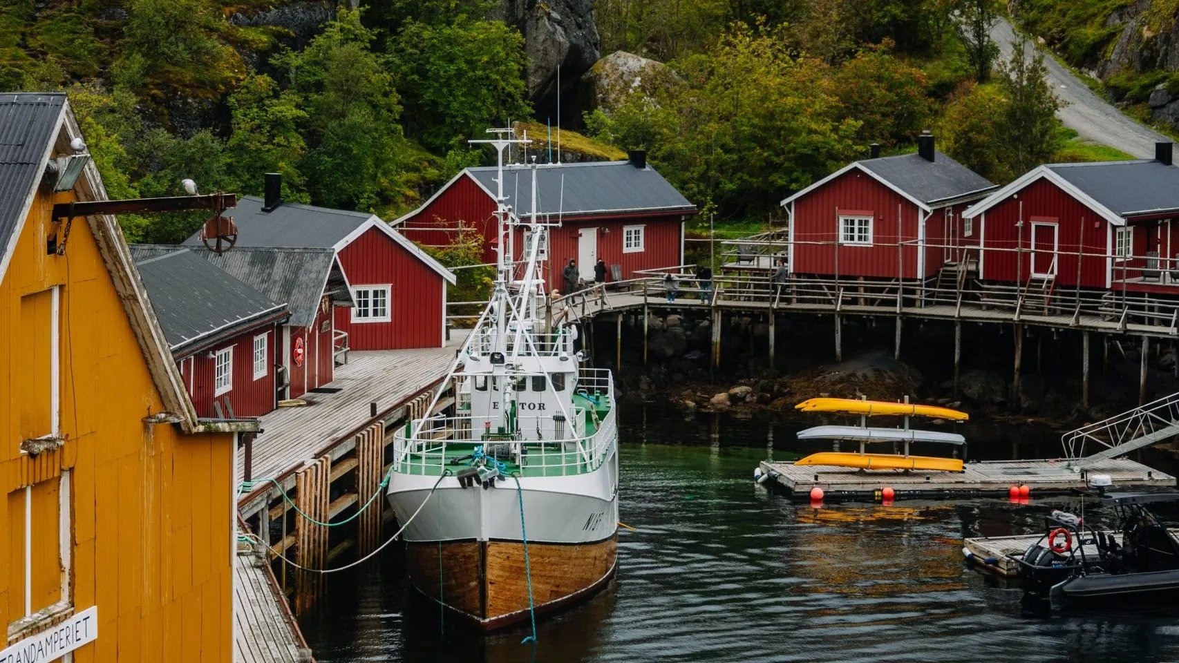 Nusfjord village with red and yellow cabins, a fishing boat docked in the foreground