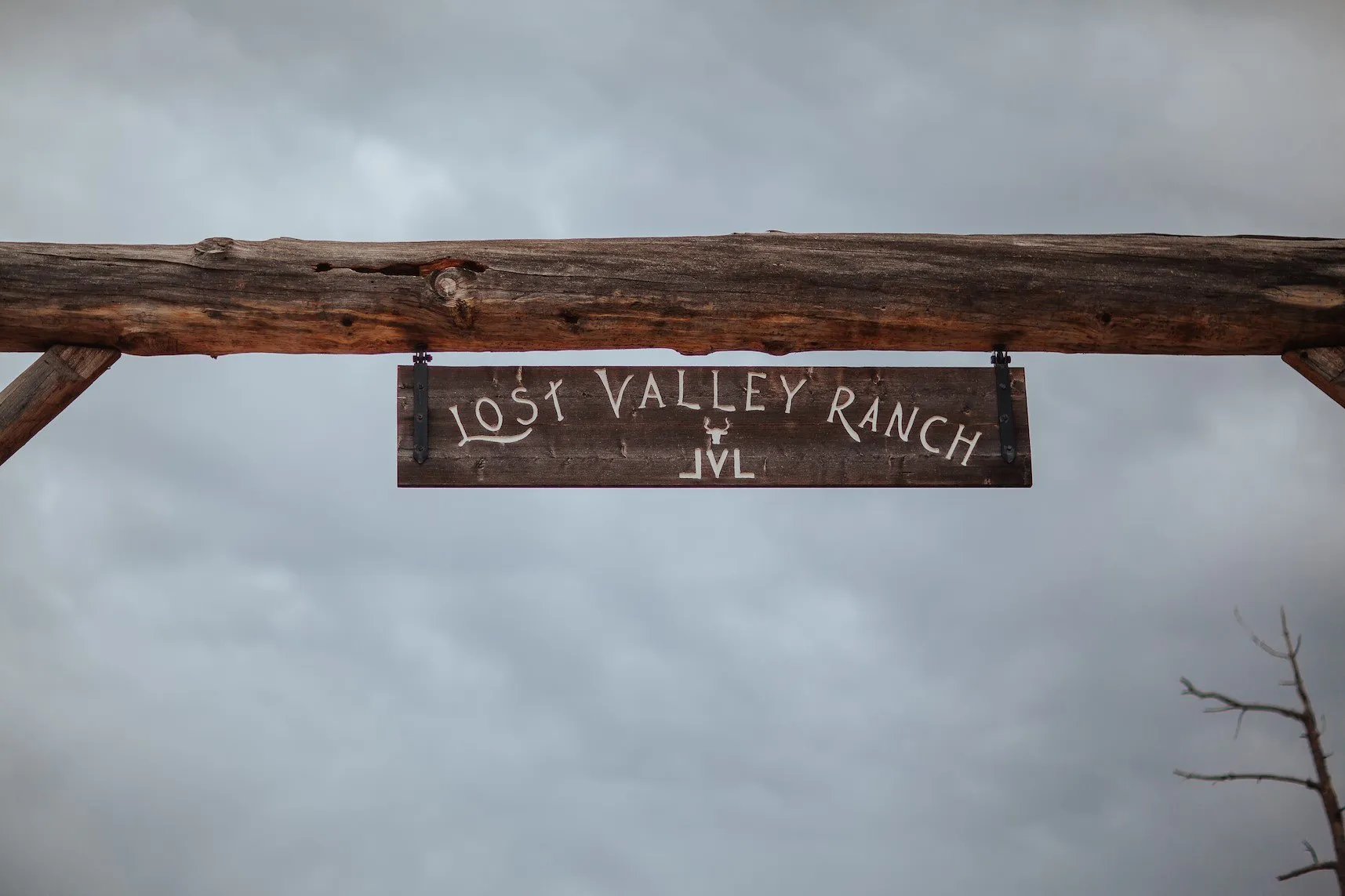 Rustic wooden archway entrance with 'Lost Valley Ranch' sign under a cloudy sky