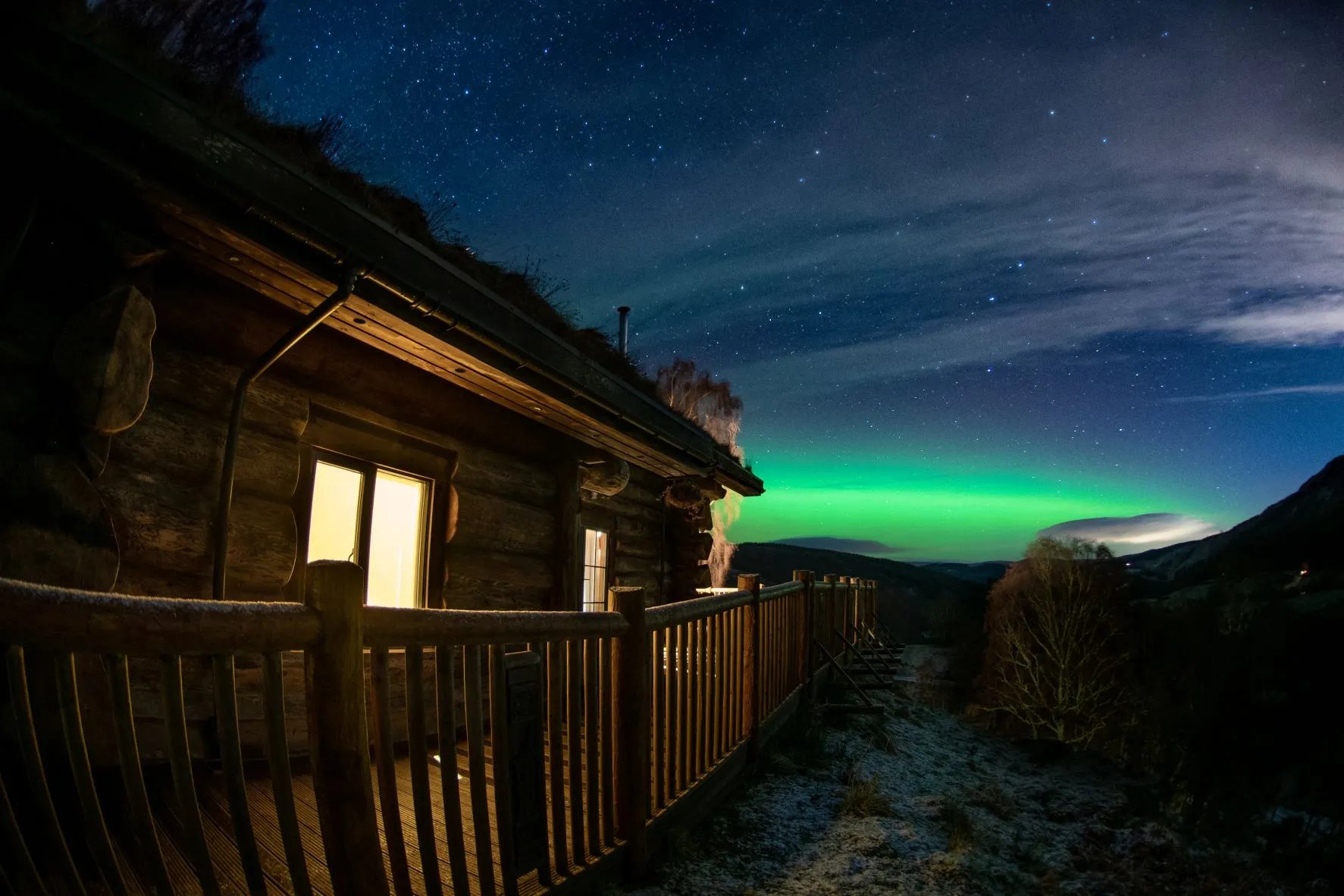 Log cabin exterior at night under the Northern Lights