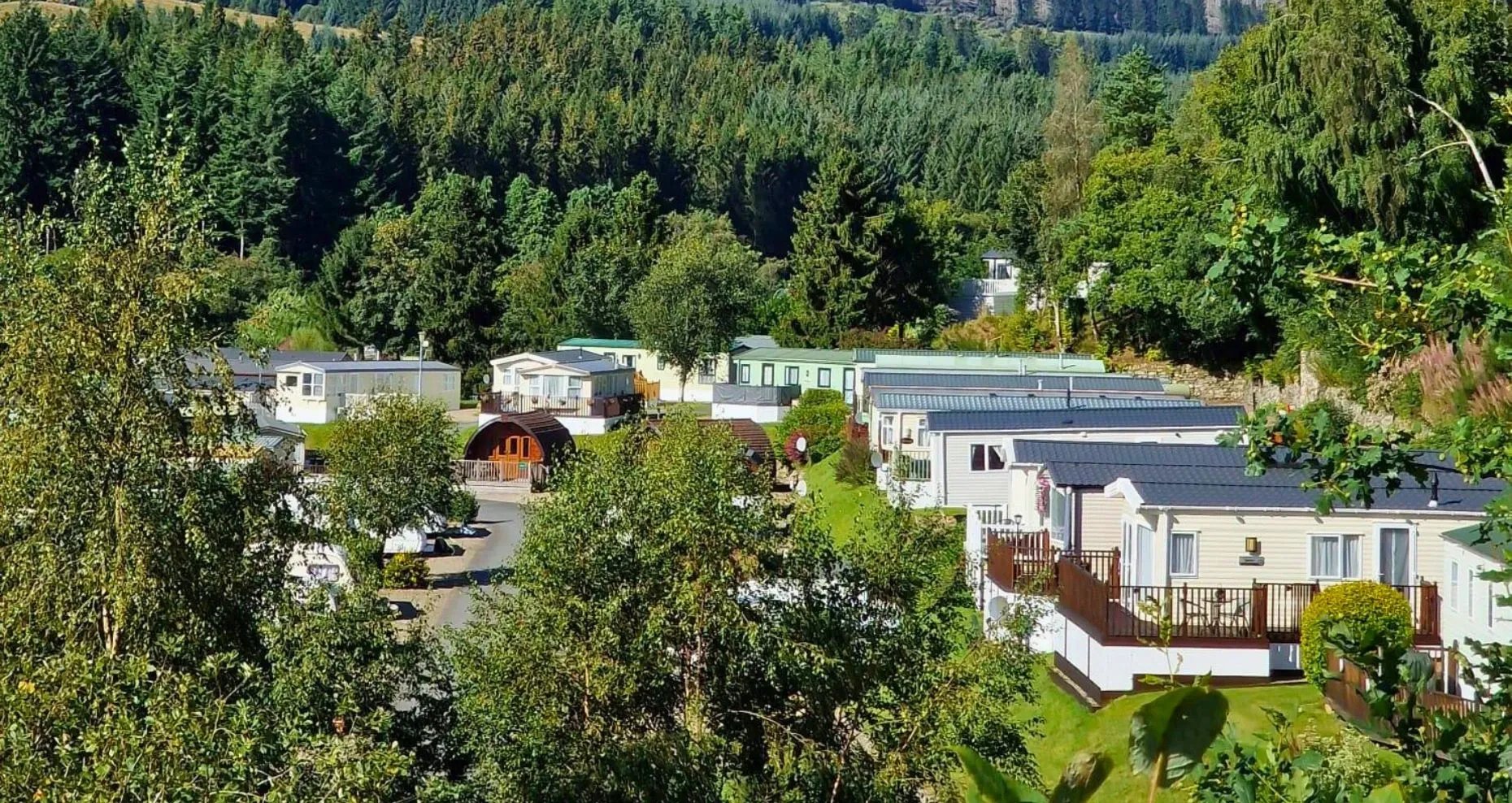 Aerial view of Corriefodly Holiday Park with caravans and lodges in a wooded valley.