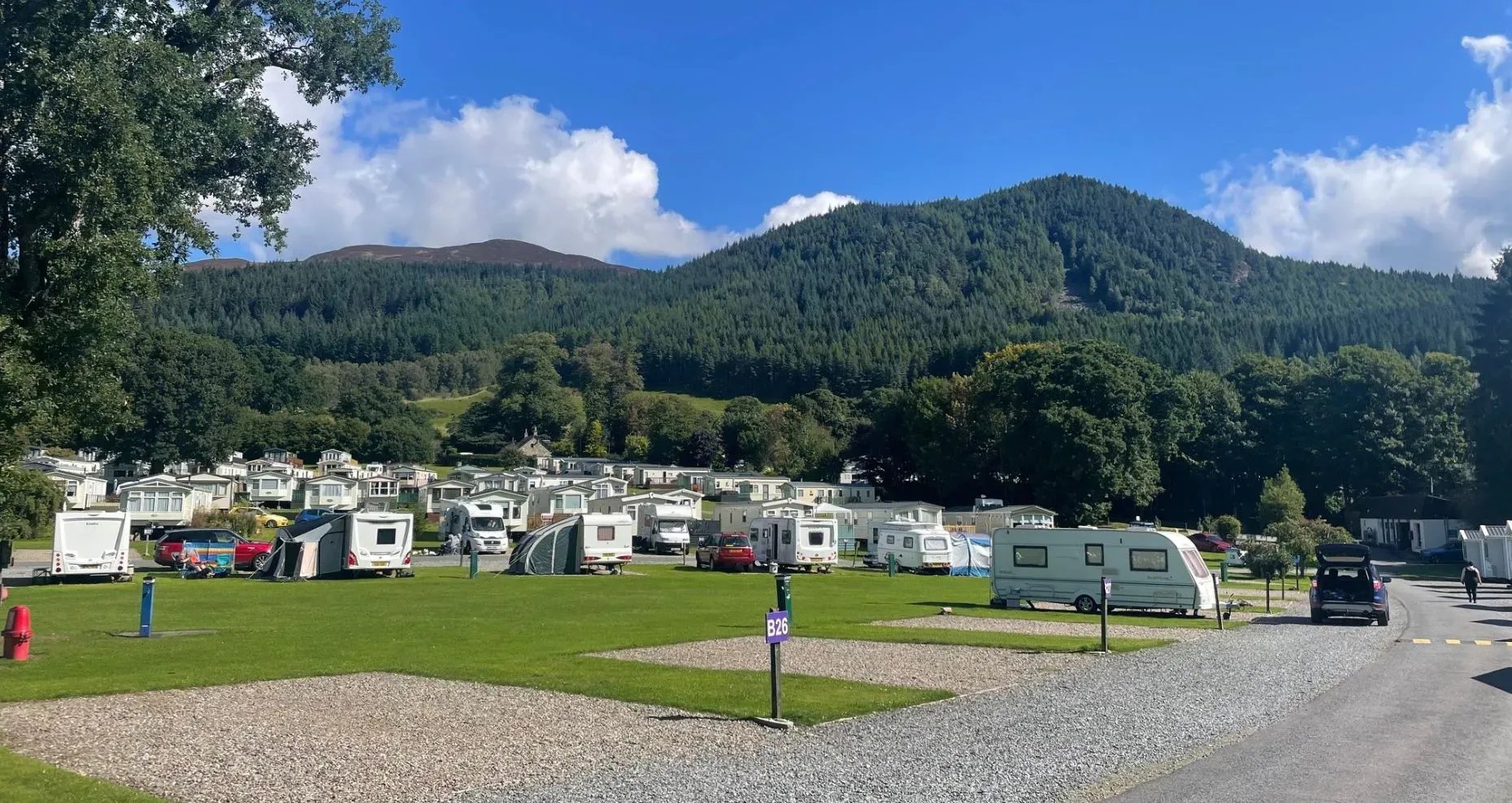 Panoramic view of Faskally Woods Holiday Park with caravans and forested mountains.