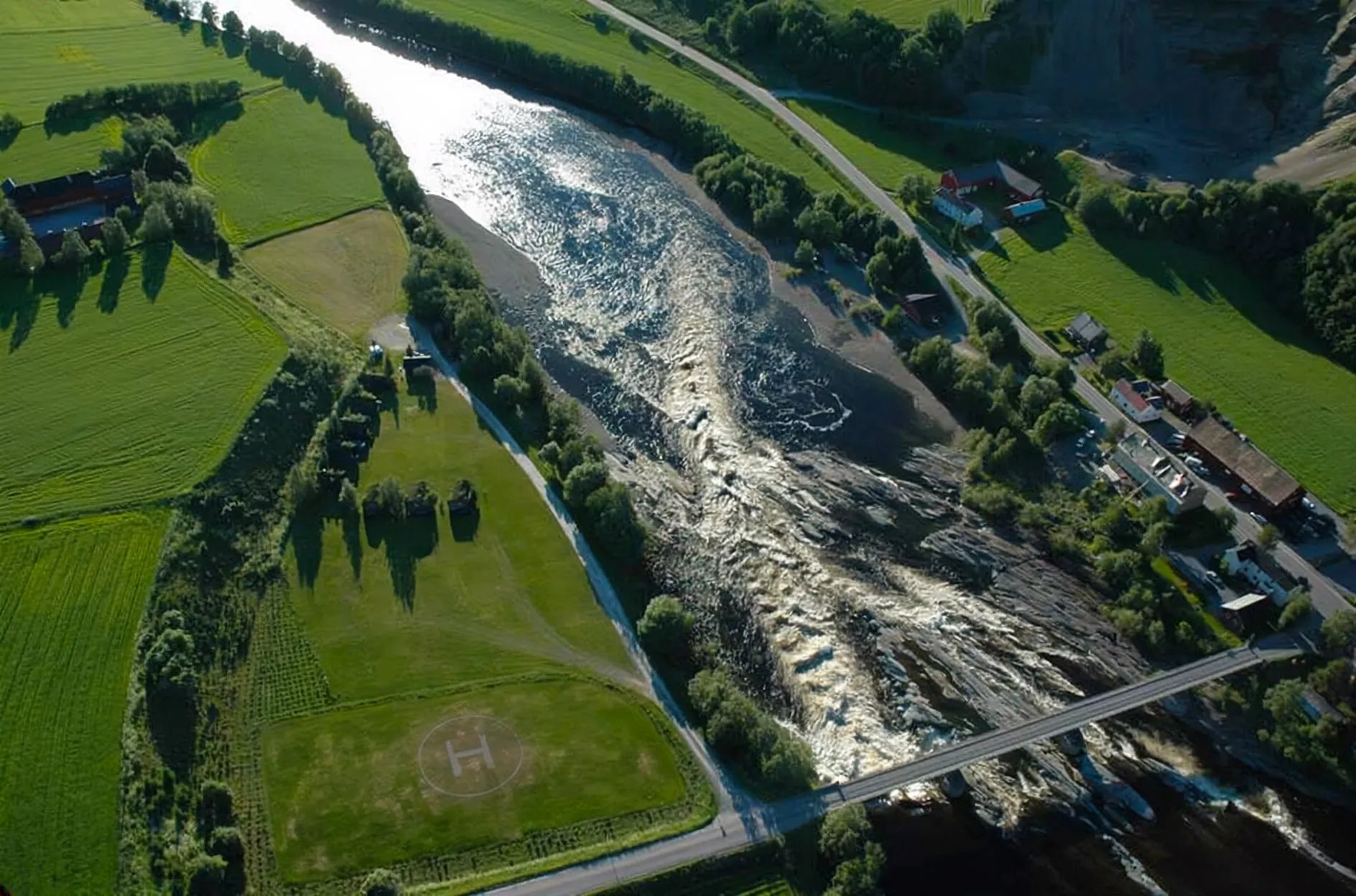 Aerial view of the Verdalselva river flowing through green fields and forests