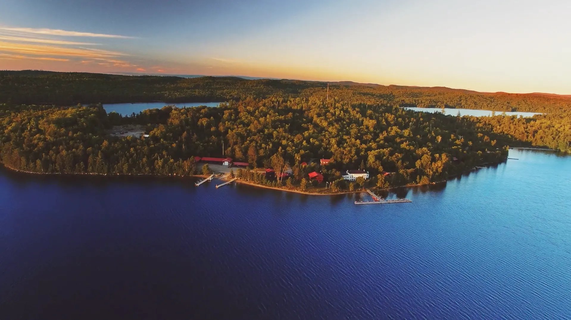 Expansive aerial view of the Beauchene lodge complex nestled on a large lake peninsula