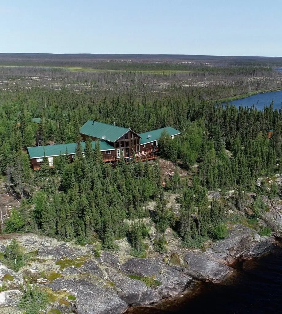 Lodge exterior with large windows glowing warmly at sunset