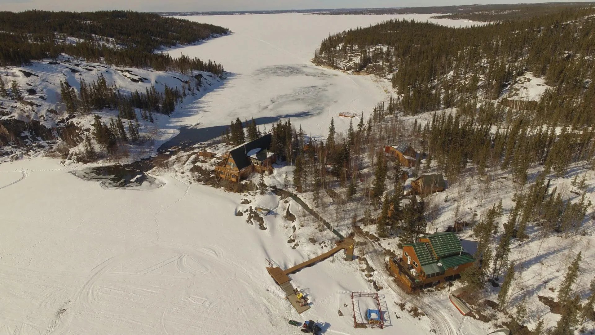 Winter aerial view of Yellow Dog Lodge buildings and docks surrounded by snow and frozen lake