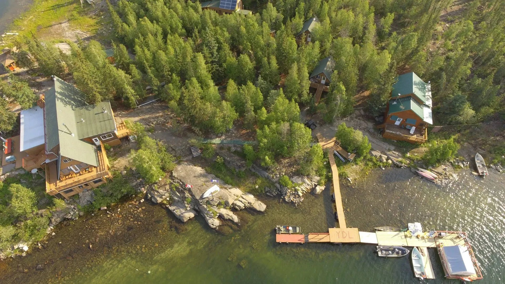 Aerial view of Yellow Dog Lodge compound nestled among green trees on a lake peninsula with multiple docks and boats