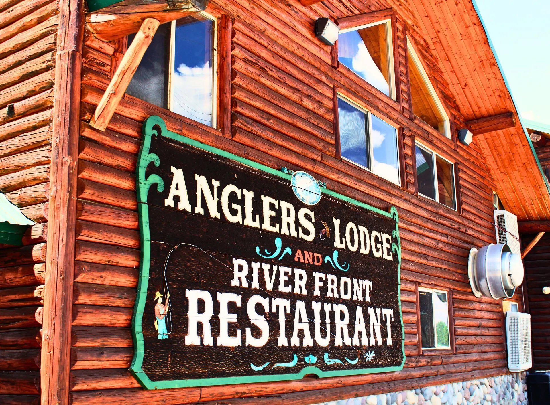 Log lodge exterior with a large sign reading 'ANGLERS LODGE AND RIVER FRONT RESTAURANT'