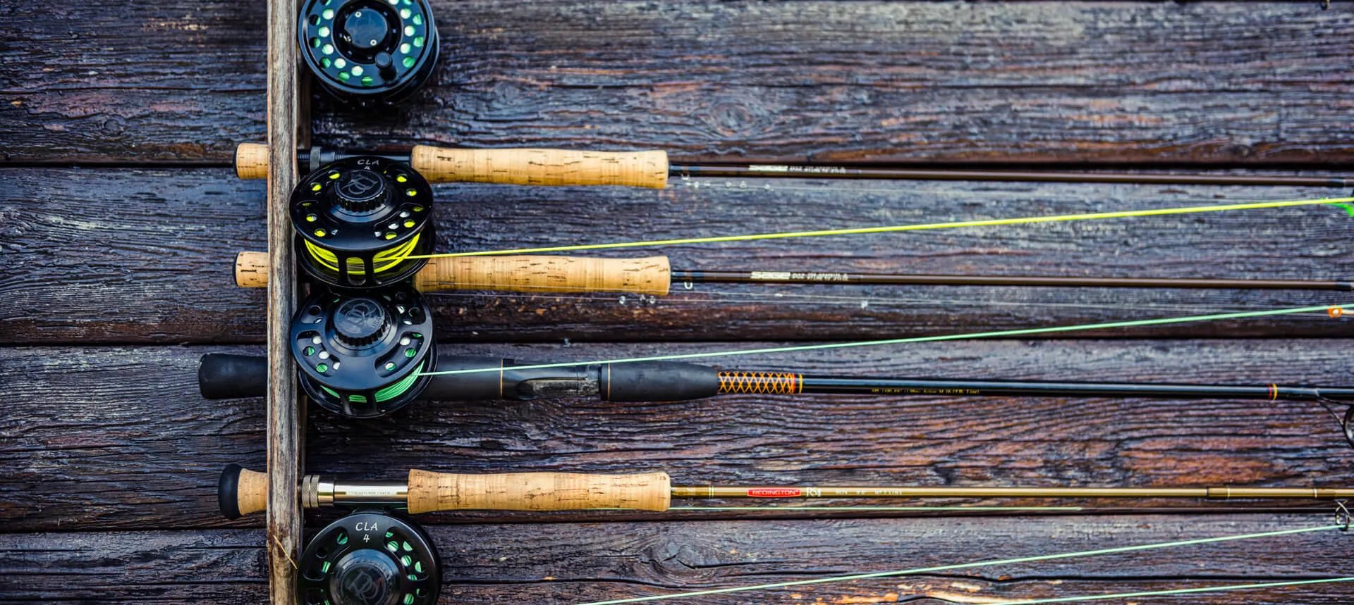 Fly fishing rods and reels neatly arranged on a rustic wooden wall