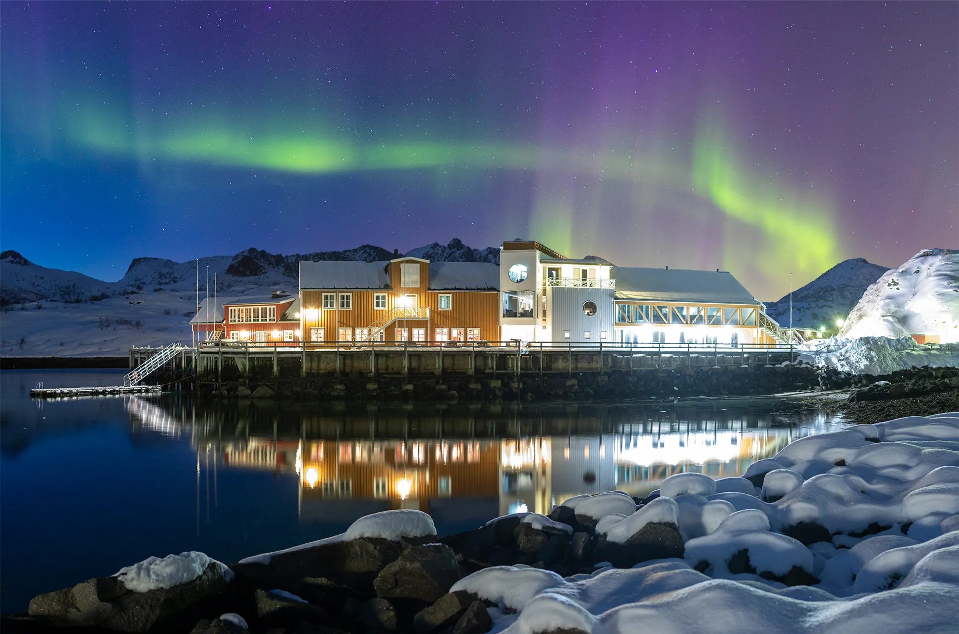 Main lodge building illuminated at night with vibrant Northern Lights dancing overhead