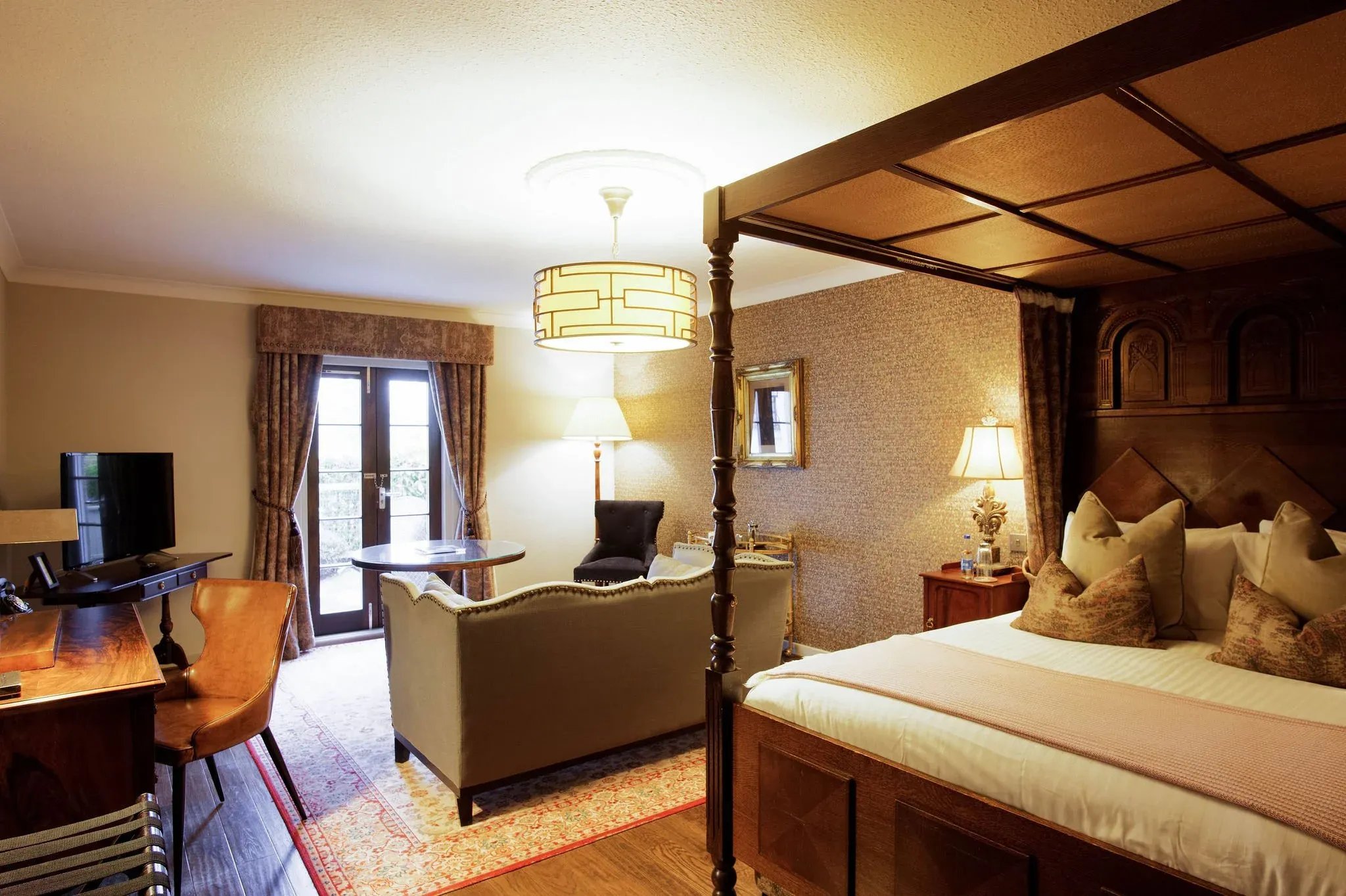 Elegant bedroom with a four-poster bed, sofa, and French doors