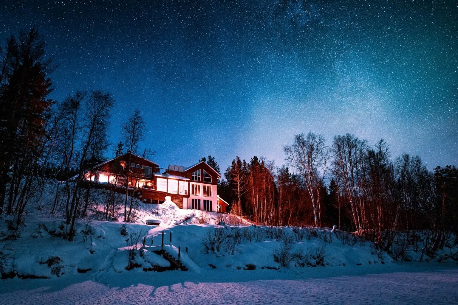 Modern lodge building with large windows reflecting the snowy winter landscape.