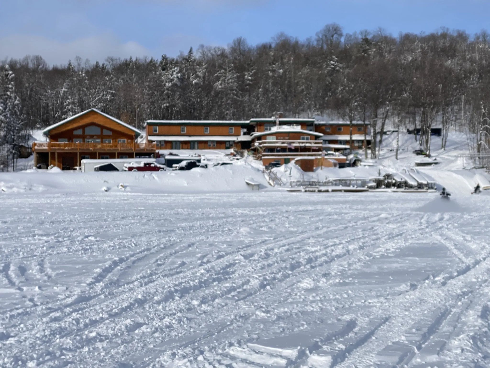 AJ's Lodge & Oven buildings on the snowy lakefront in winter, surrounded by forest