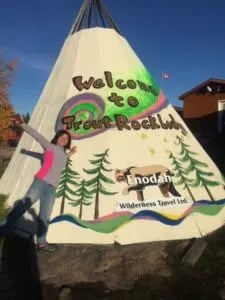 Woman posing in front of a painted teepee welcoming visitors to Trout Rock Lodge.