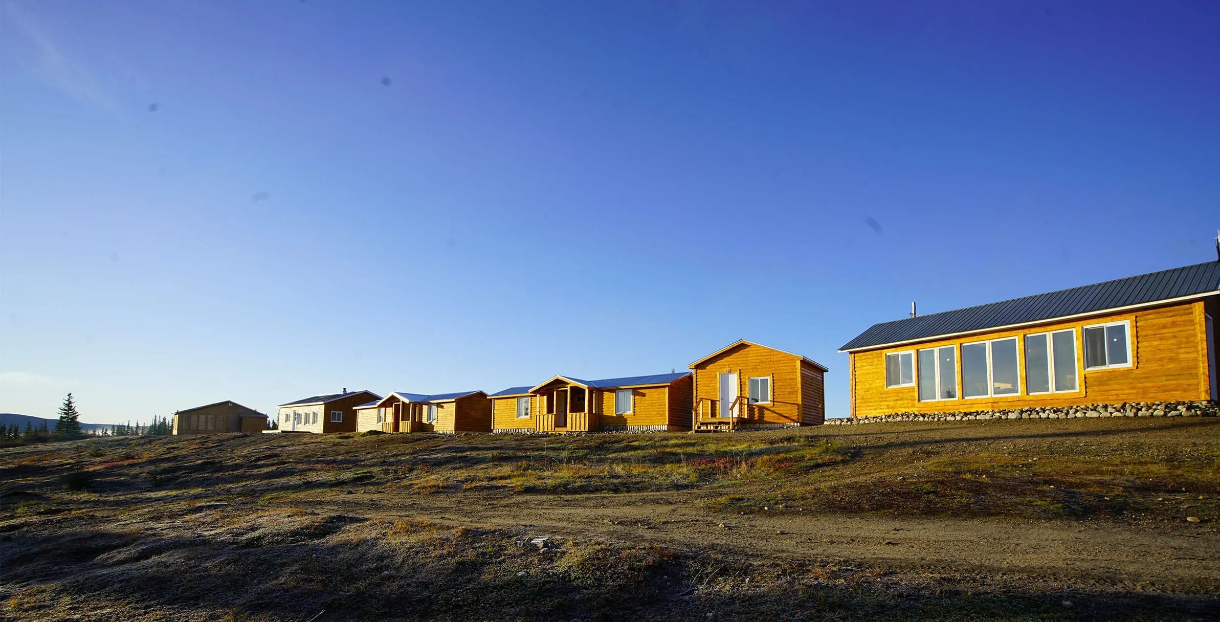 Row of wooden lodge buildings under a clear blue sky