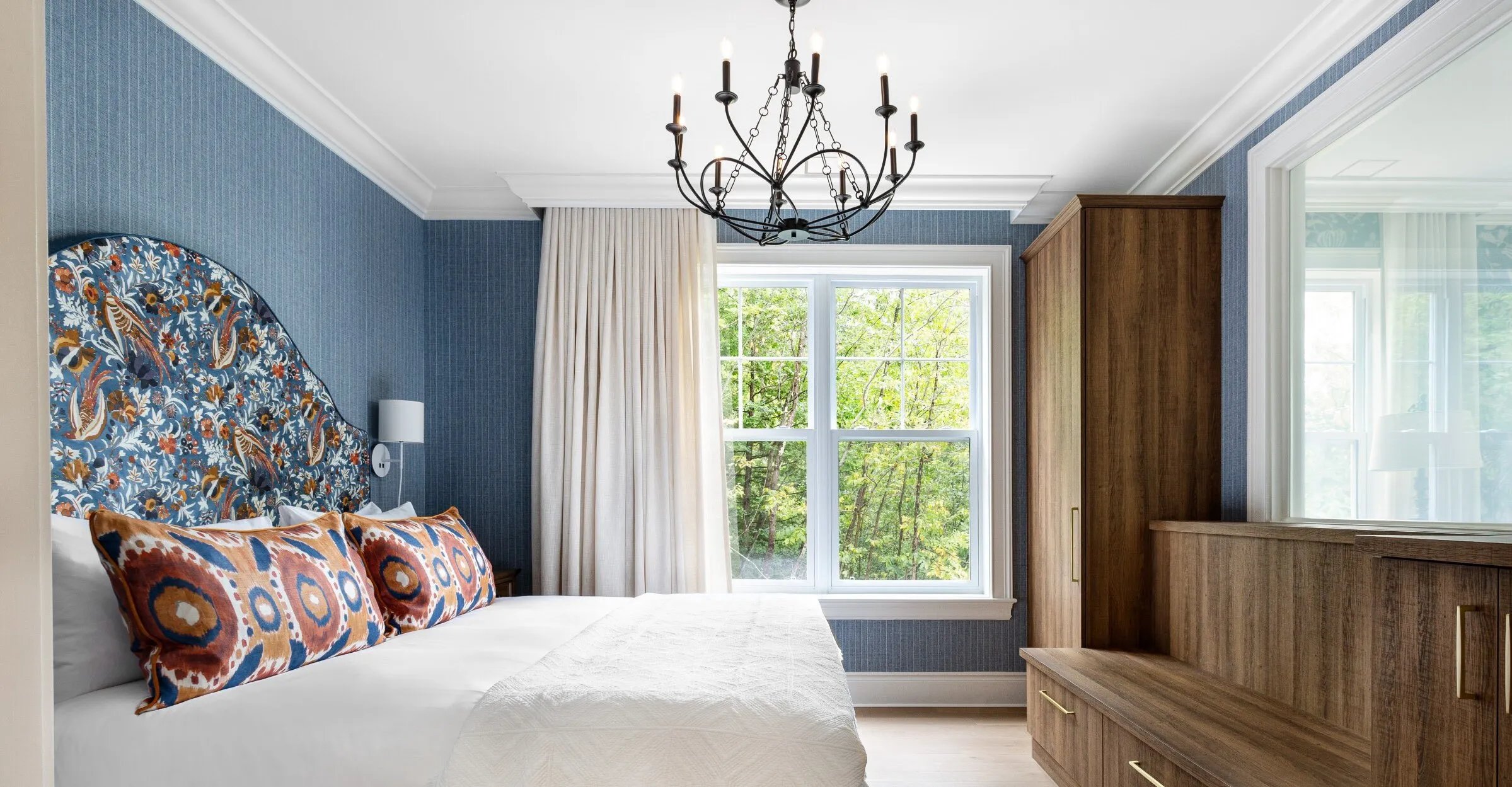 A bed in a bright suite with large window
