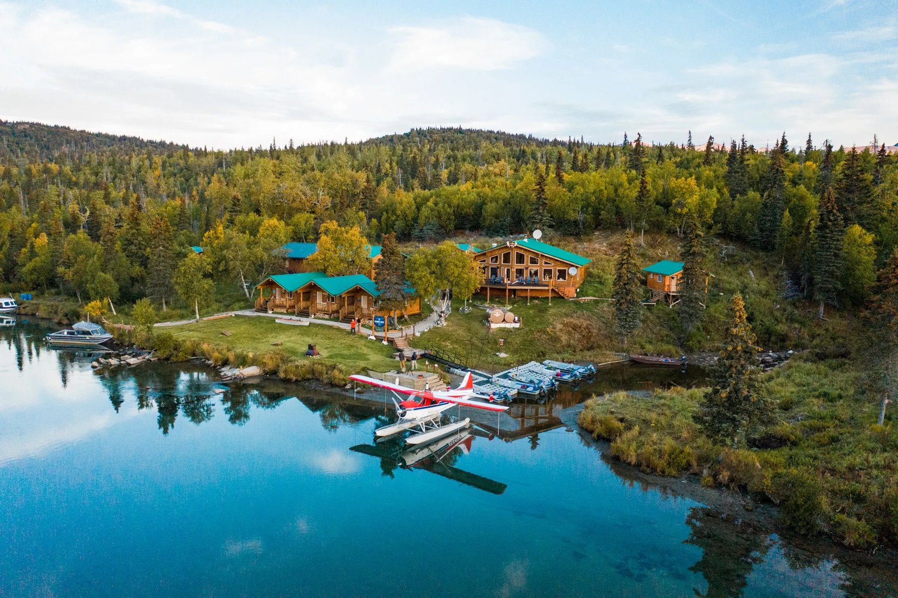 Panoramic view of the Iliamna River Lodge cabins along the lake shore under a bright sky