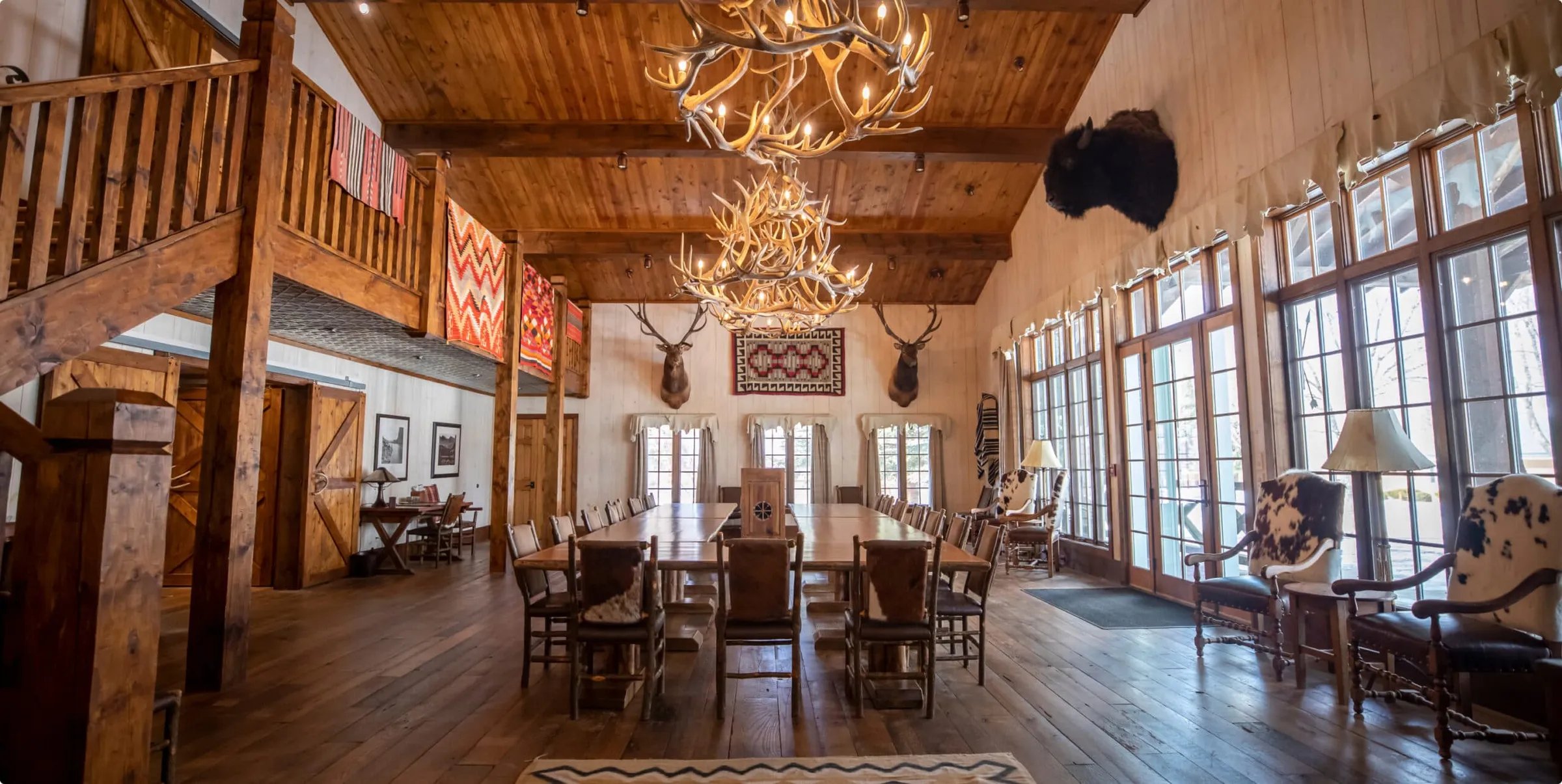 Grand Heritage Hall with high wooden ceilings, antler chandeliers, and large windows