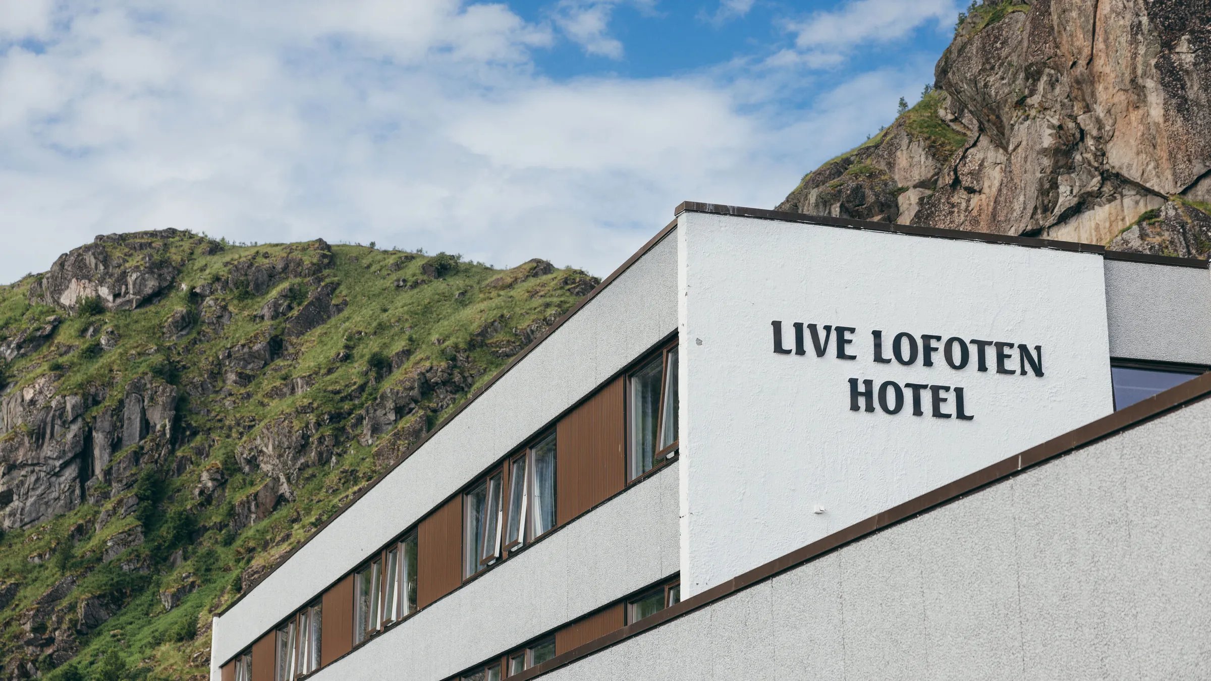 Modern Live Lofoten Hotel building with mountain backdrop under a blue sky