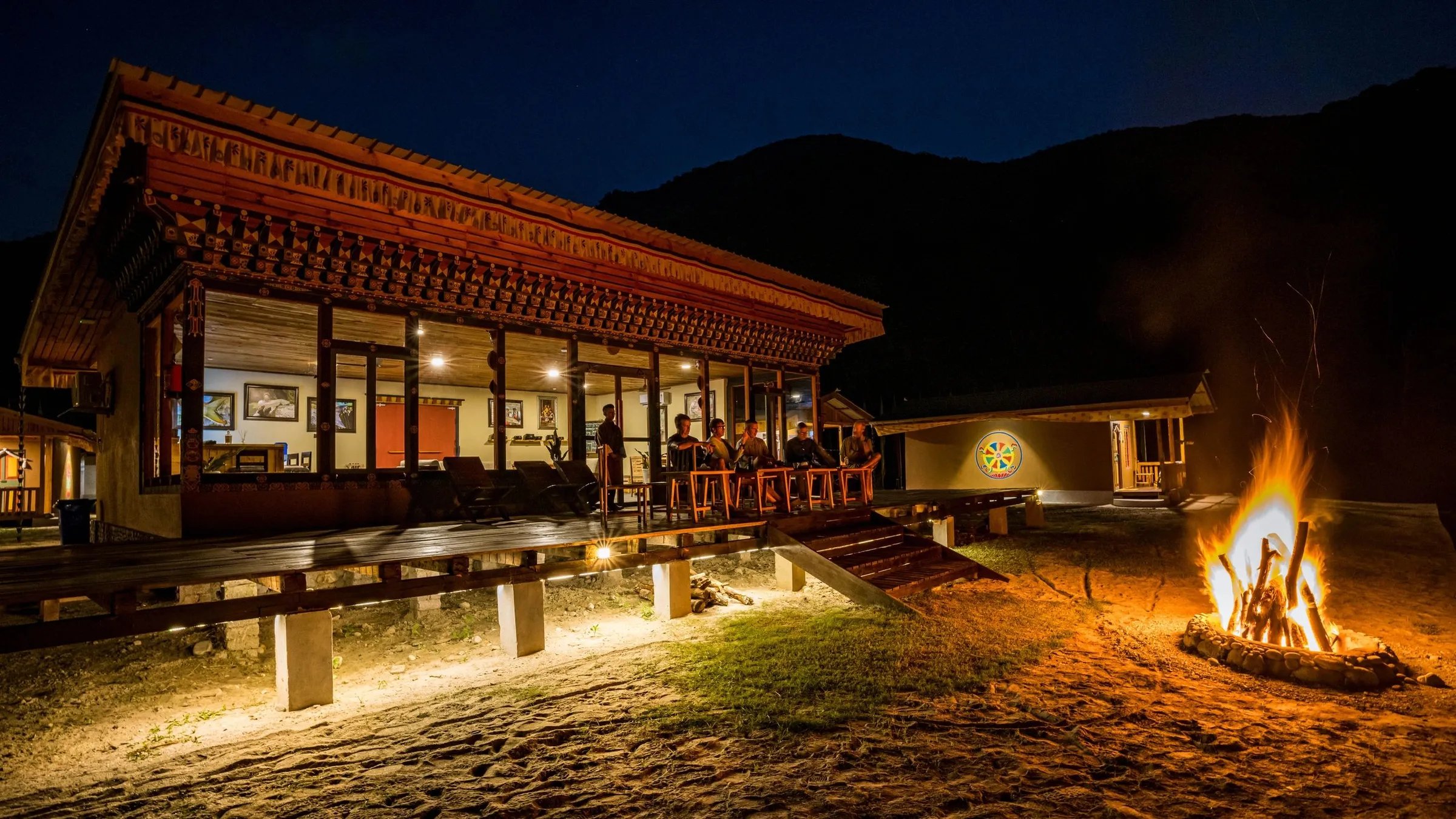 Lodge building illuminated at night with a crackling campfire in the foreground