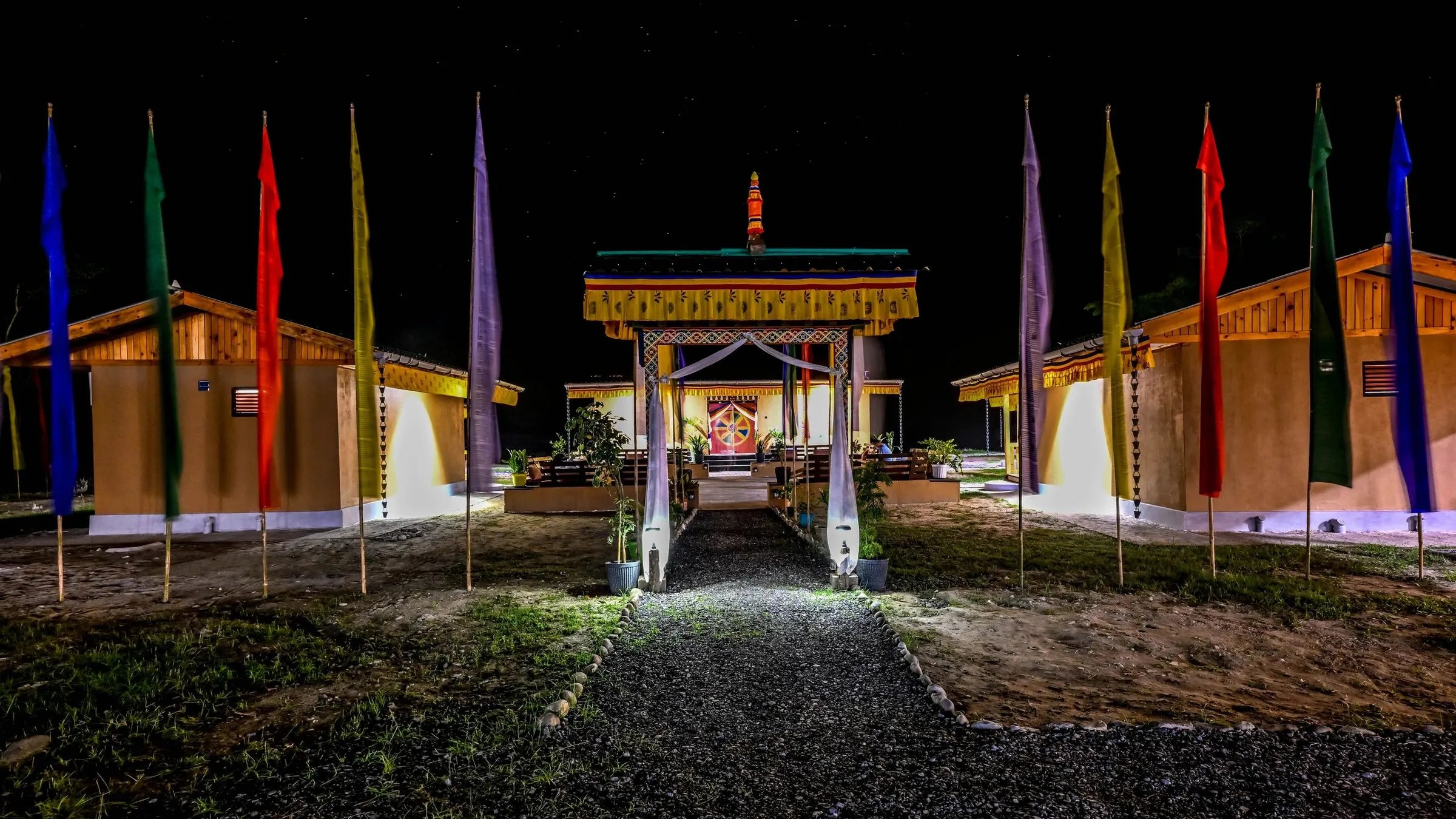 Lodge entrance at night, with a lit pathway lined by colorful prayer flags