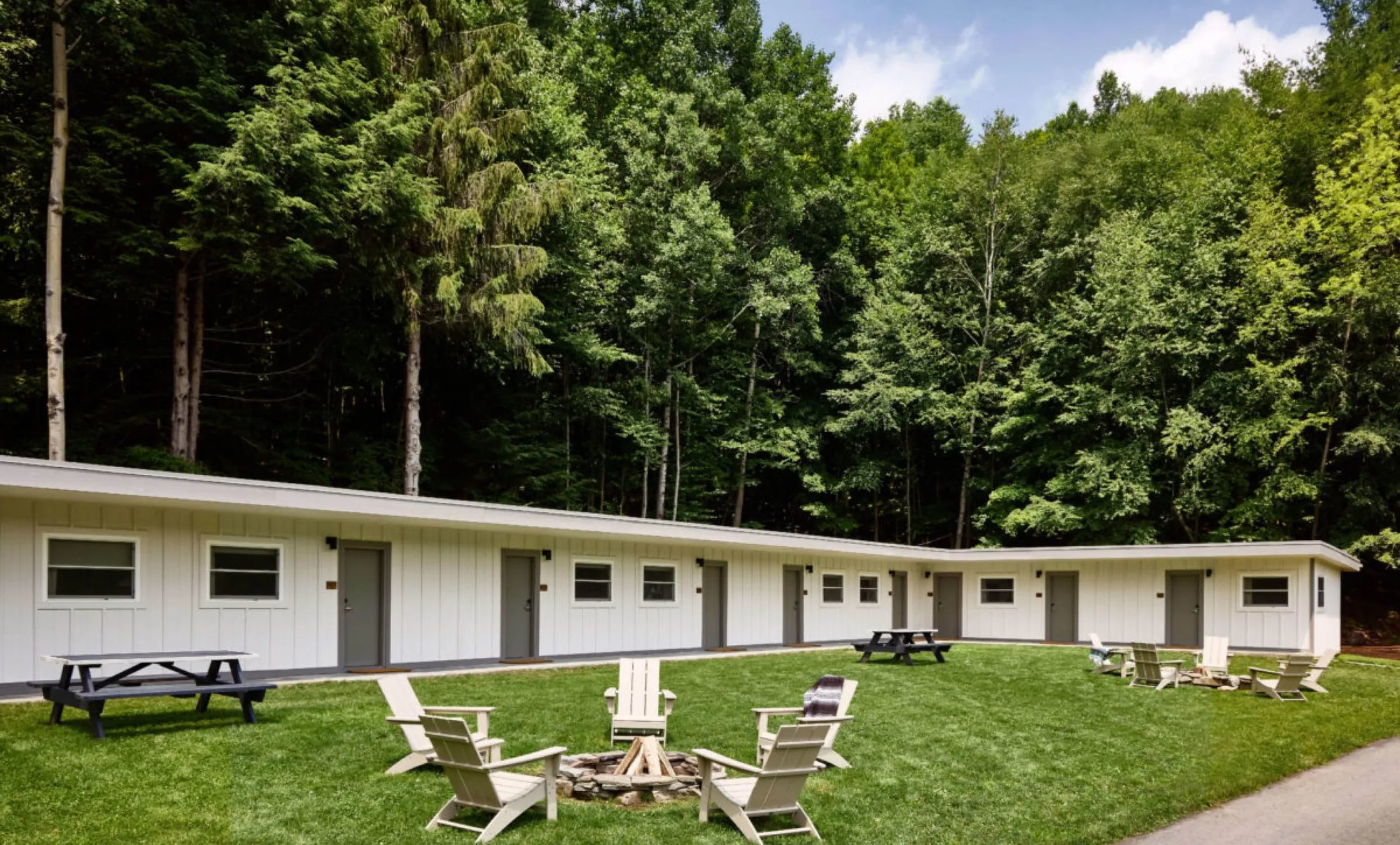 Modern Pool House building with wood paneling and multiple balconies against a green hillside