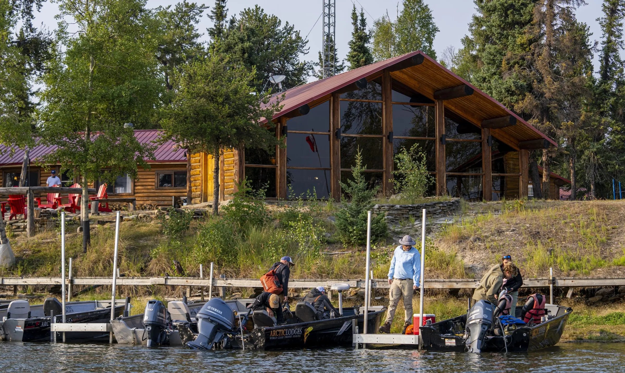Main lodge building seen from the water with fishing boats docked in front