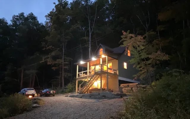 Penn York Haven lodge exterior at night, warmly lit, with the lodge name overlaid in yellow script.
