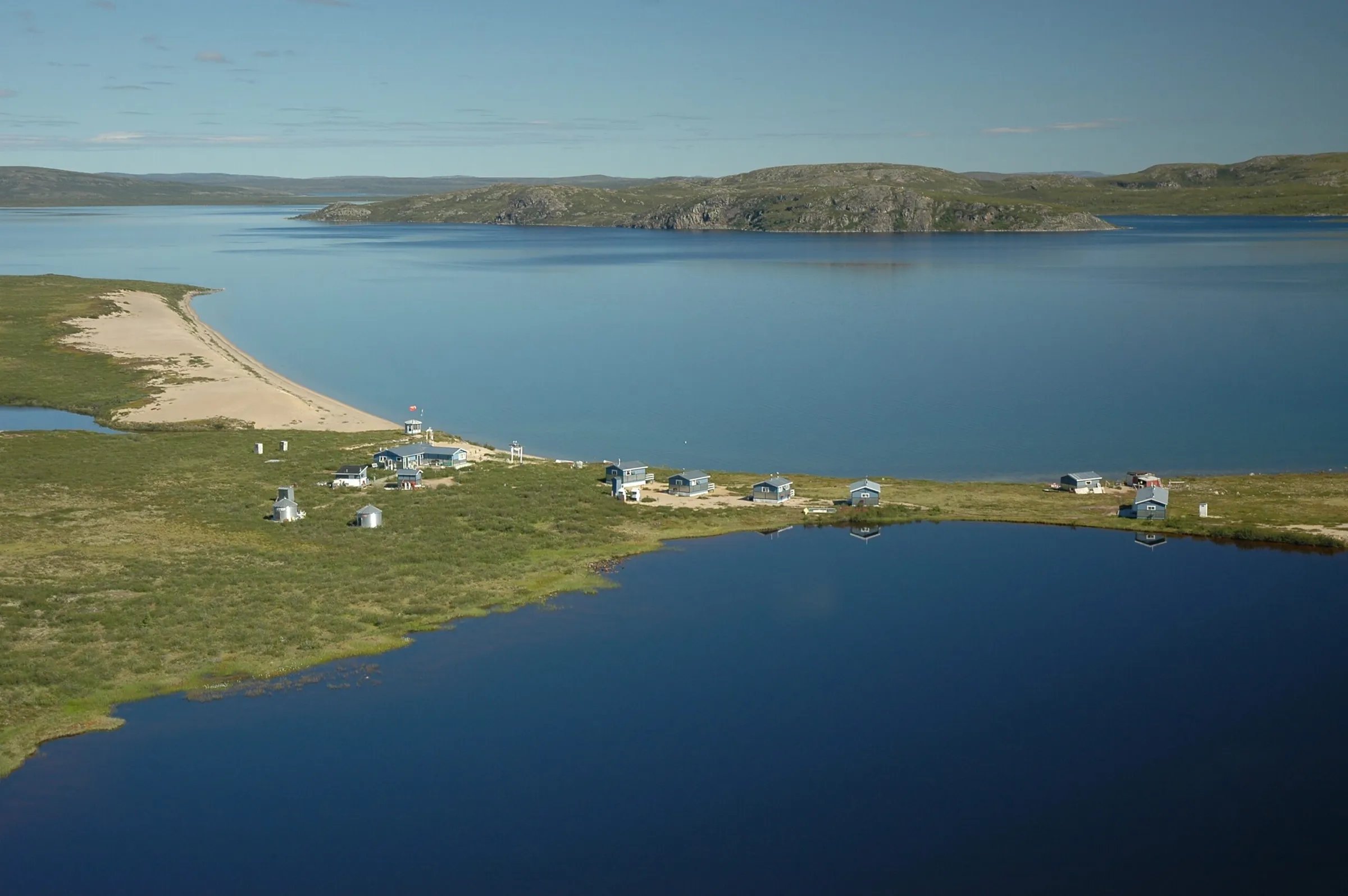 Aerial view of Peterson's Point Lake Lodge on a peninsula between two lakes under a clear sky.