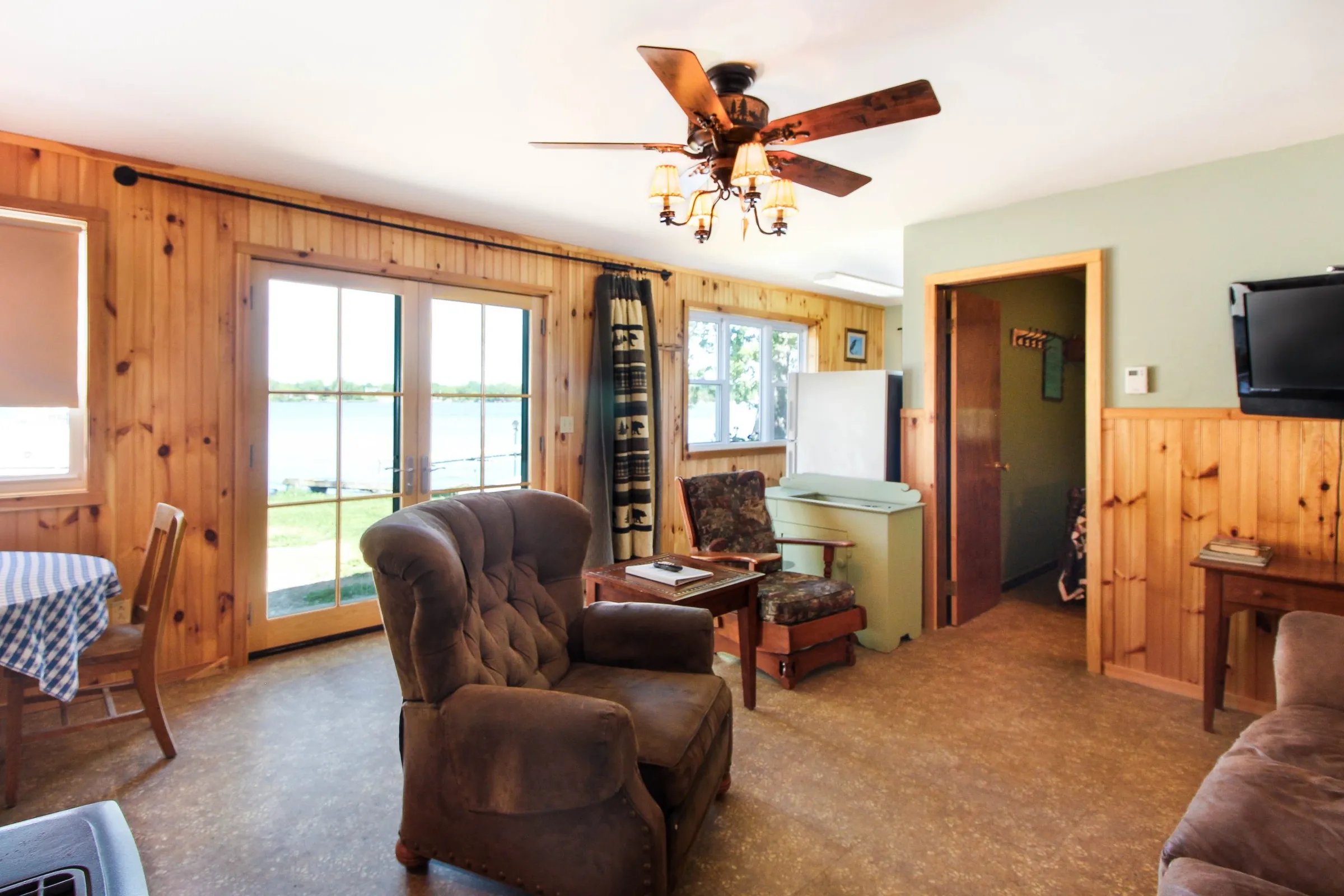 Private 2-bedroom cabin interior with wood paneling, armchair, and sliding door to the lake