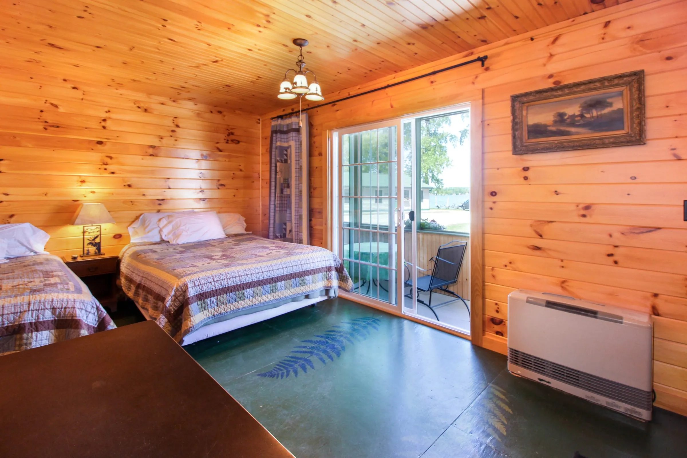 Rustic motel-style room with two beds, wood paneling, and a screened porch