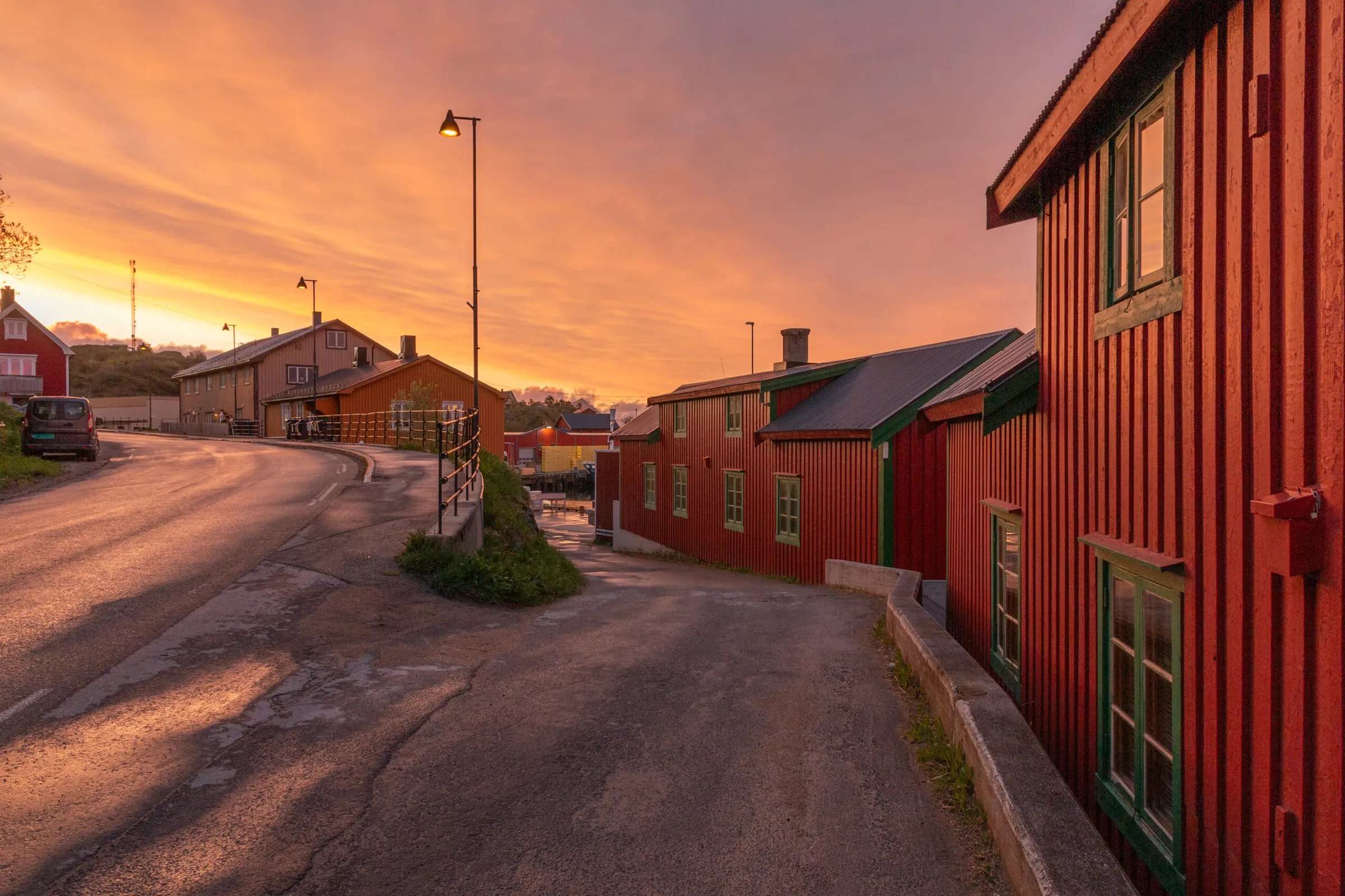 Traditional red buildings lining a street at sunset, with an orange sky