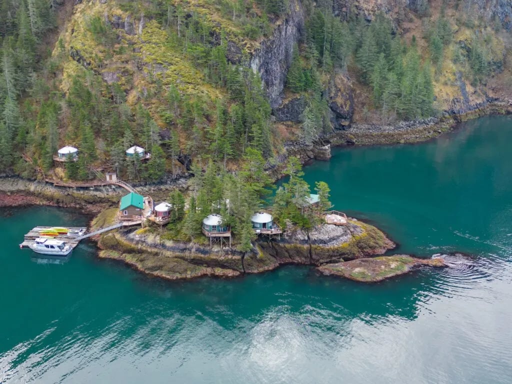 Four guests looking out over Humpy Cove from a boardwalk, with the lodge and docks in the distance.
