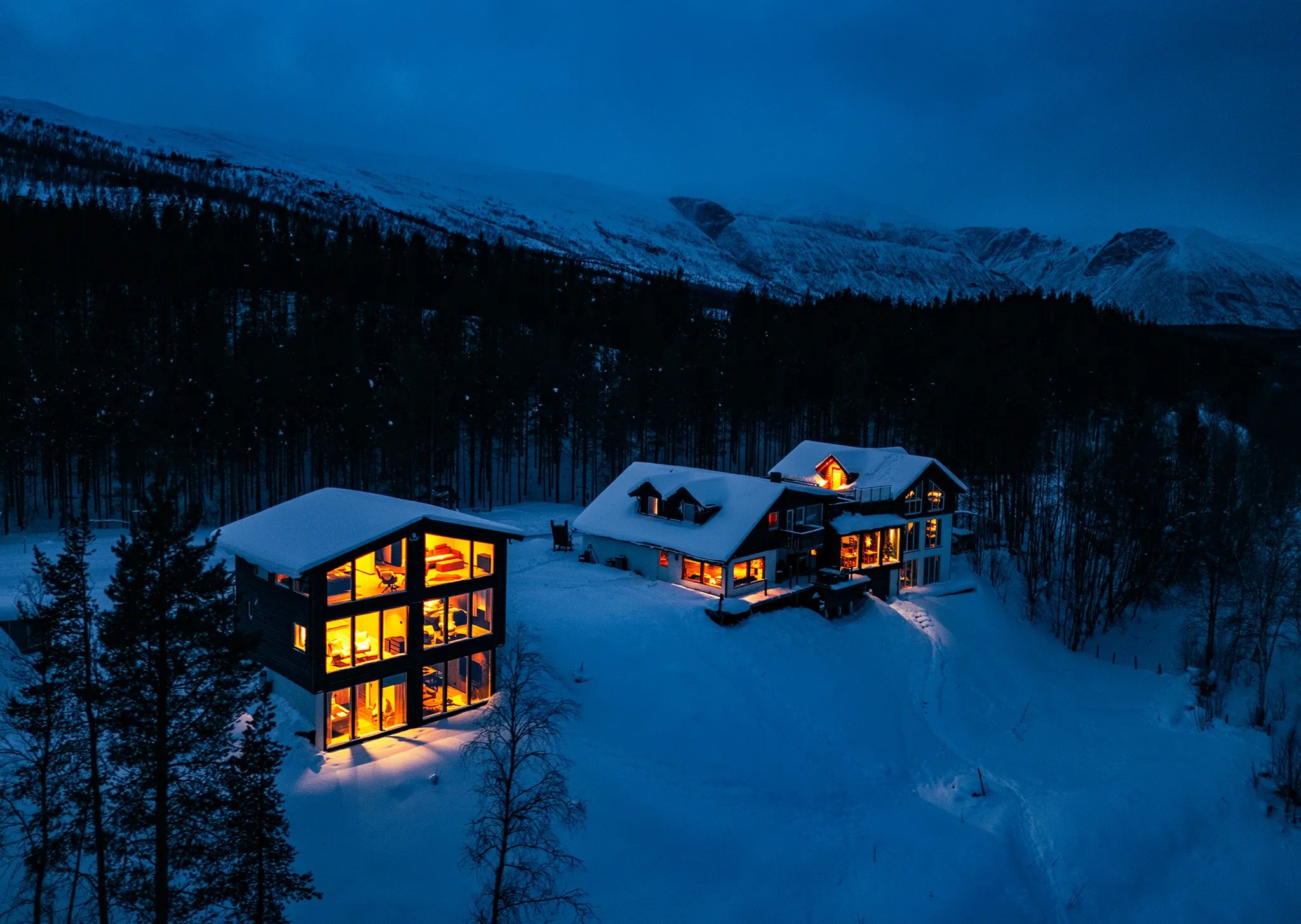 Reisa Lodge exterior illuminated under vibrant pink and green Northern Lights in winter.