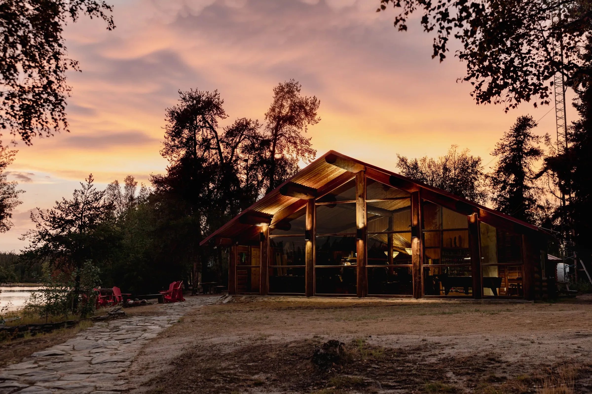 Lodge building with large windows illuminated at sunset