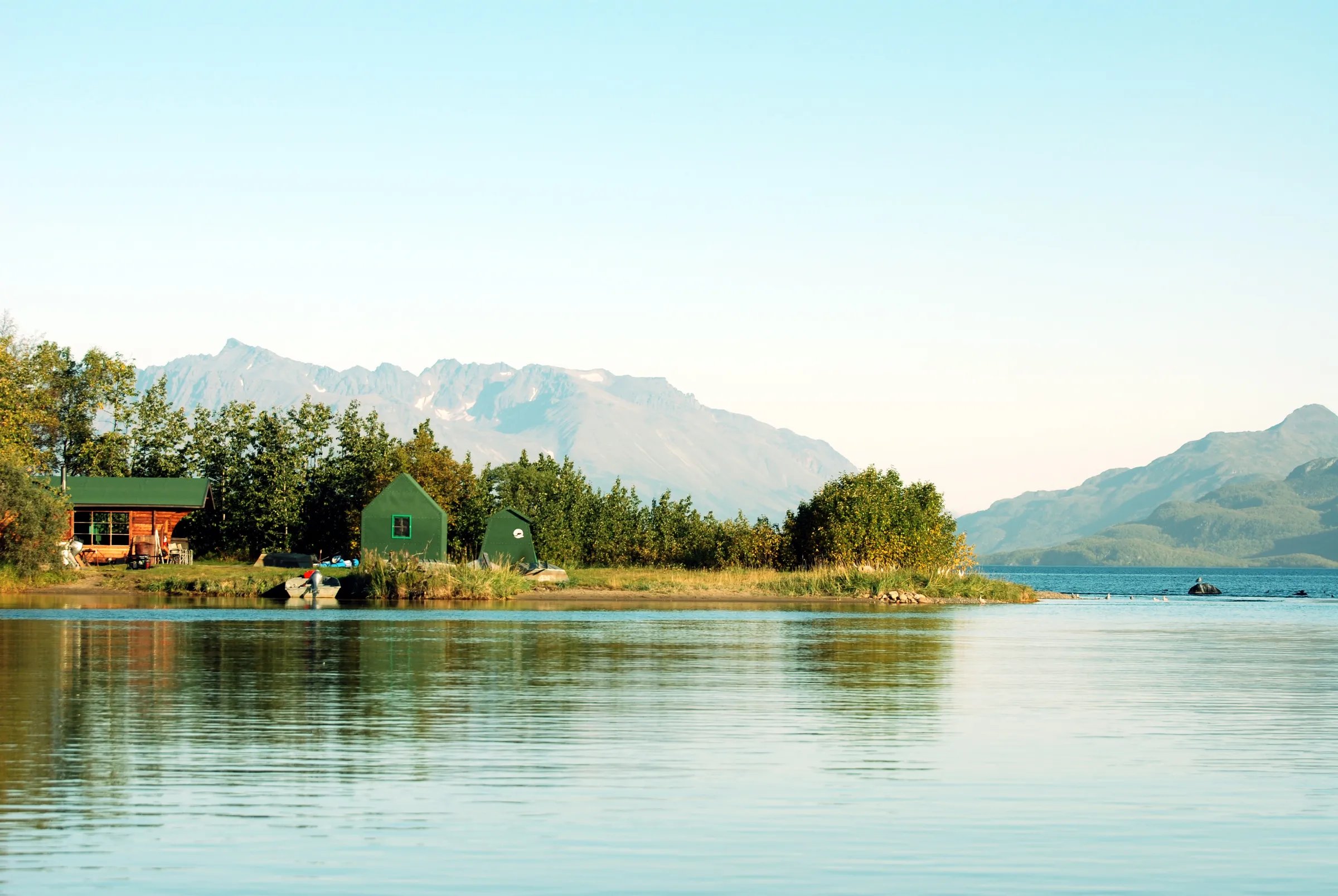 Grosvenor Lodge buildings nestled on a calm lake shore with mountains in the background.