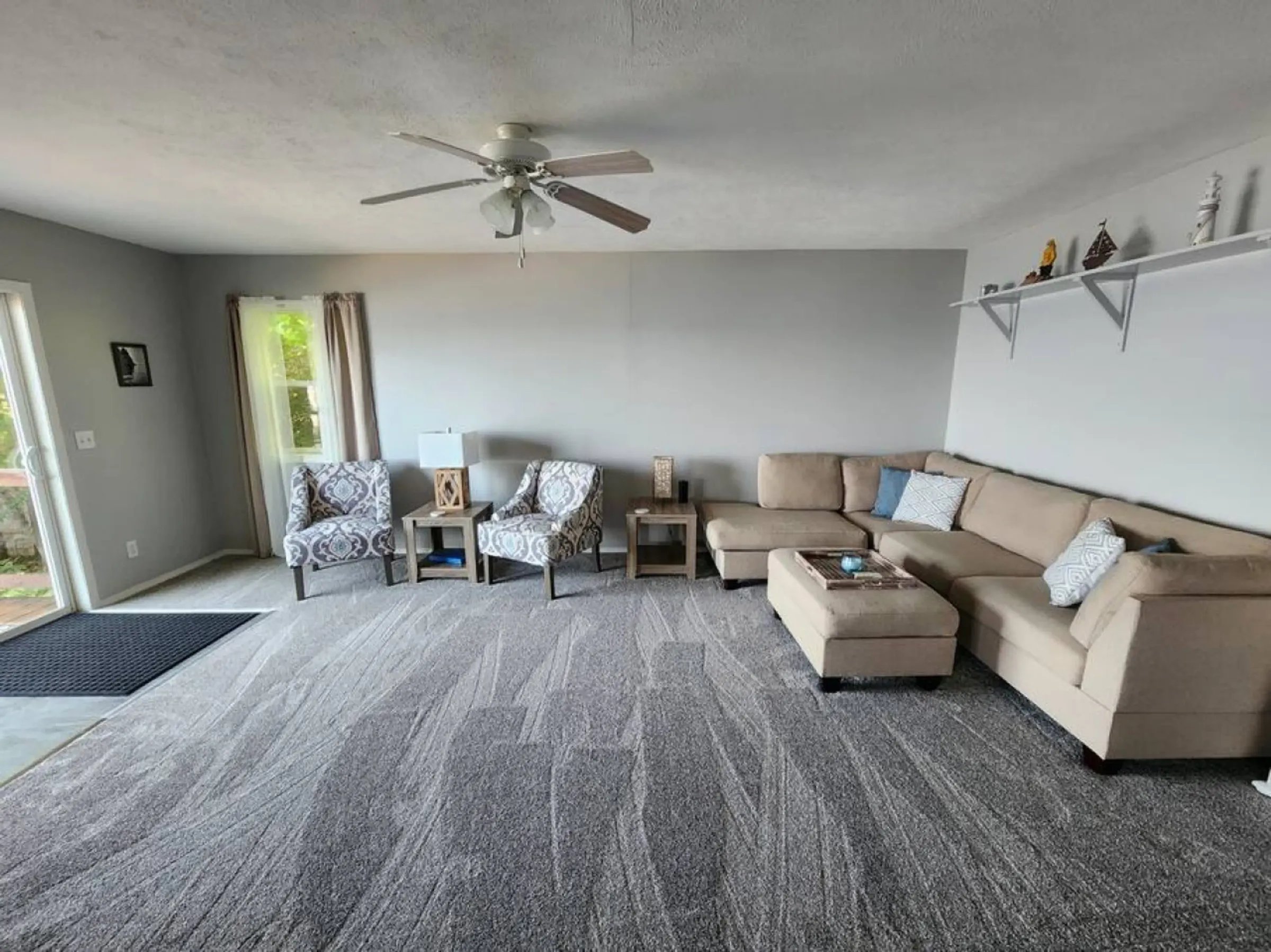 Modern living room with a large L-shaped sectional sofa and ceiling fan