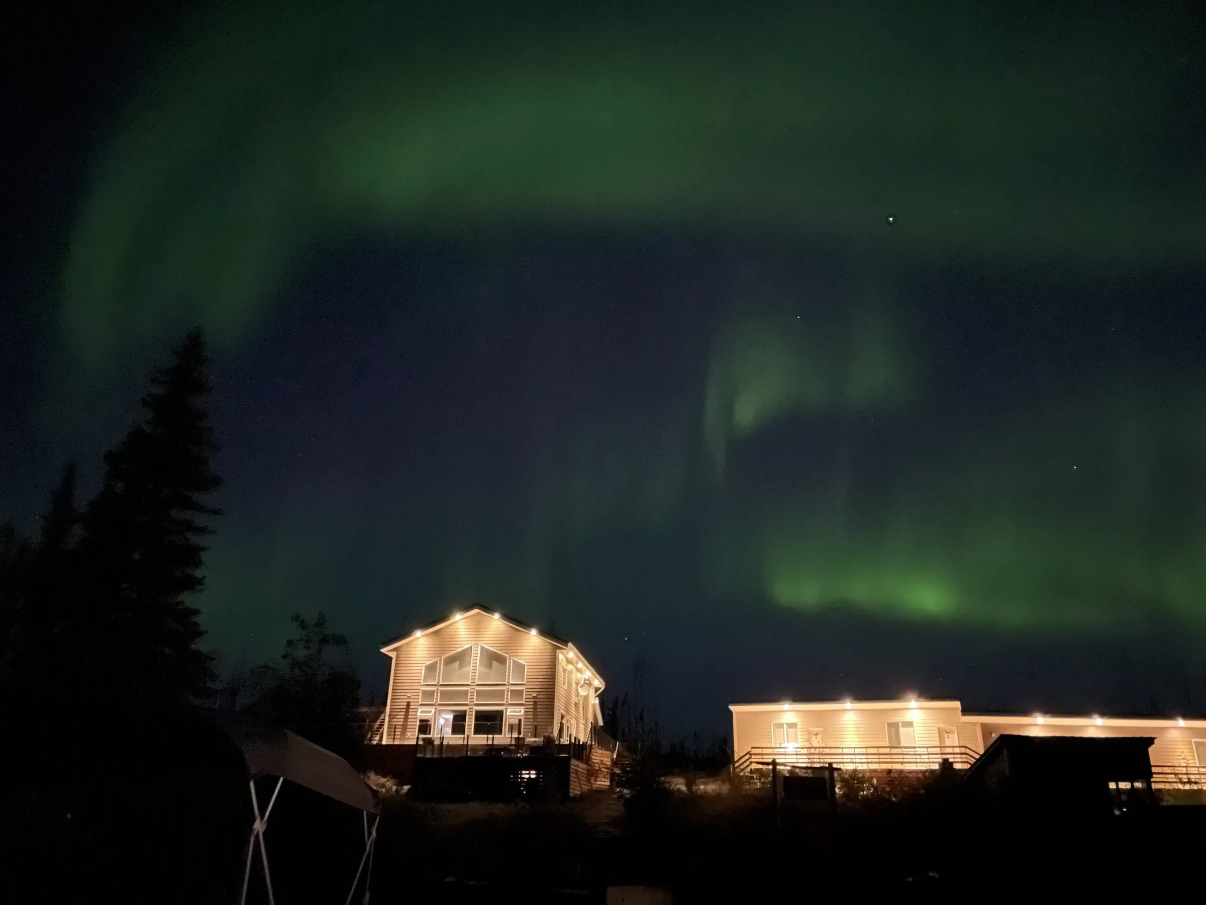 Namushka Lodge buildings illuminated under a vibrant green aurora borealis sky