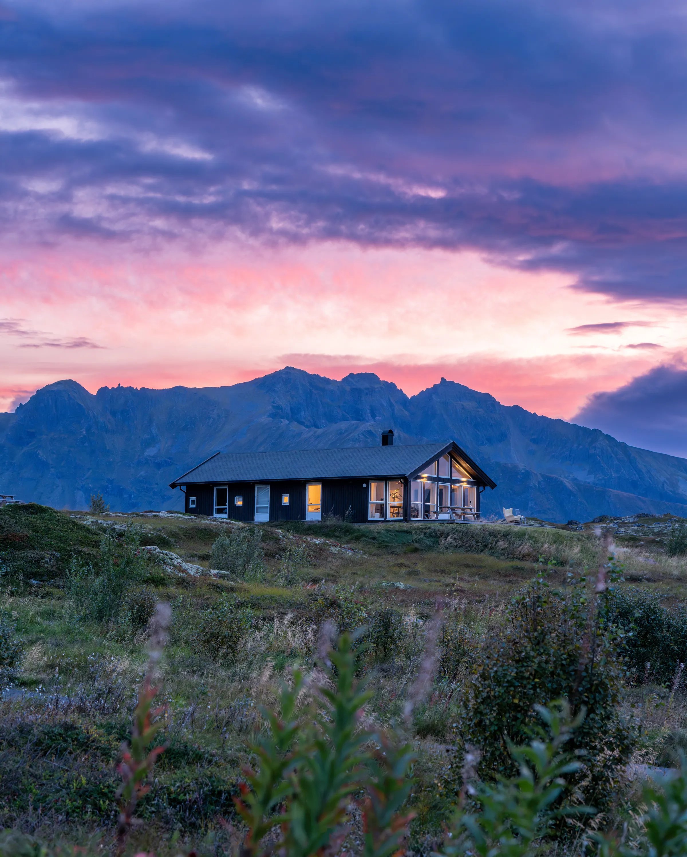 Modern lodge building on a hill under a vibrant pink and purple sunset sky