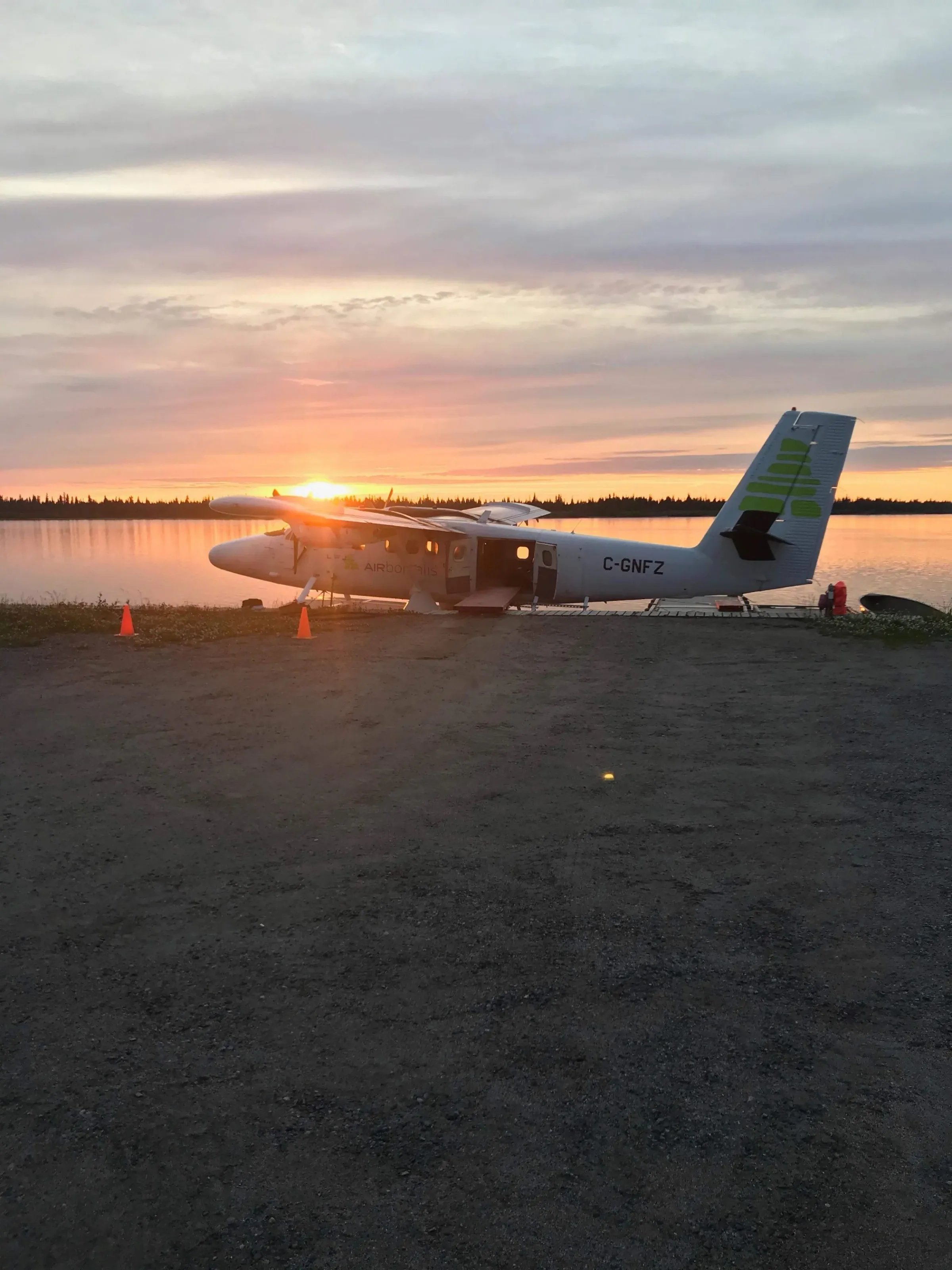 Floatplane parked on a lake shore with a vibrant sunset in the background