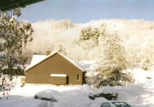 Small lodge building surrounded by snow-covered trees in winter
