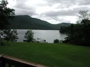 Wooden docks extending into a calm lake with forested mountains under a clear blue sky