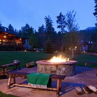 Outdoor fire pit area with stone benches and lodge buildings at dusk