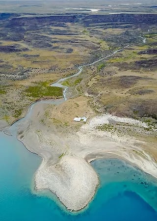 Aerial view of a winding river meeting a large lake, with small buildings on the shore