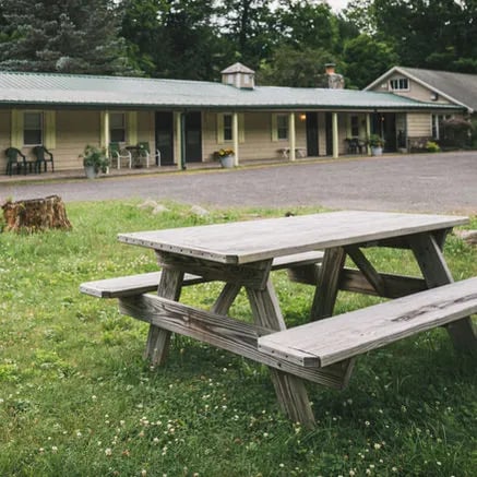 Motel-style lodge building with a green roof and a picnic table in the grassy foreground