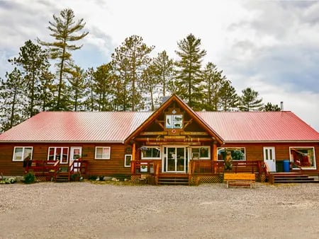 Main lodge building with a red roof and wooden exterior under a cloudy sky