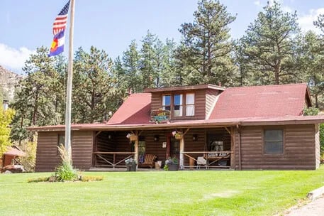 Wooden lodge building with a red roof and a Colorado flag flying on a tall flagpole