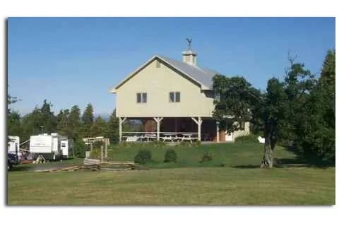 Light-colored barn-style building with a covered porch and cupola at Champlain Resort.