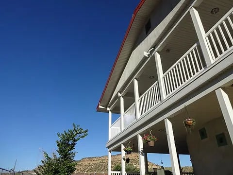 Multi-story lodge building with white balconies and a red roof under a clear blue sky